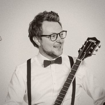 Andreas mit Brille, Fliege und Gitarre