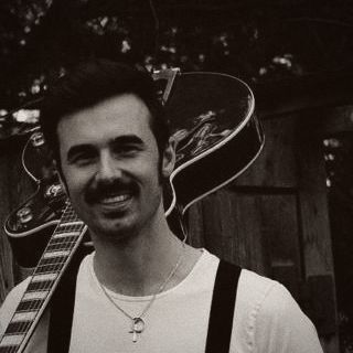 Martin mit Schnurrbart, die Gitarre über der Schulter